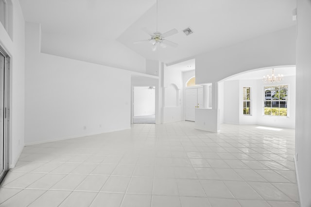 tiled empty room with ceiling fan with notable chandelier and high vaulted ceiling