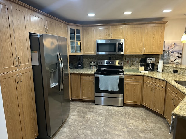 kitchen with sink, tasteful backsplash, light stone counters, decorative light fixtures, and stainless steel appliances