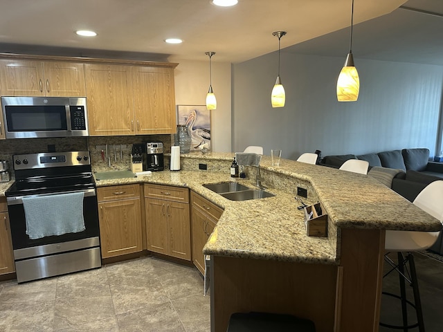 kitchen with sink, stainless steel appliances, kitchen peninsula, and a kitchen bar