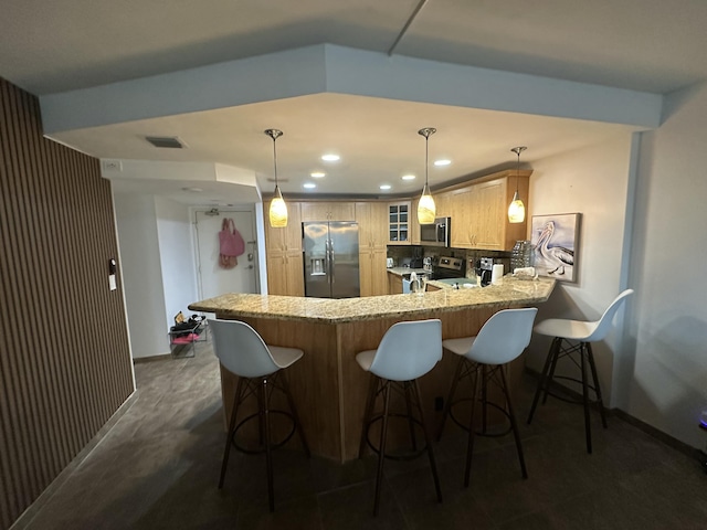 kitchen featuring appliances with stainless steel finishes, light brown cabinetry, decorative light fixtures, backsplash, and kitchen peninsula