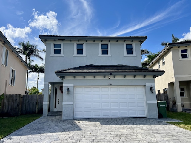 view of front facade with a garage, decorative driveway, fence, and stucco siding