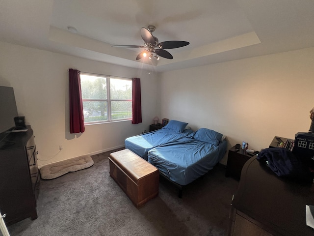 carpeted bedroom featuring a raised ceiling and ceiling fan