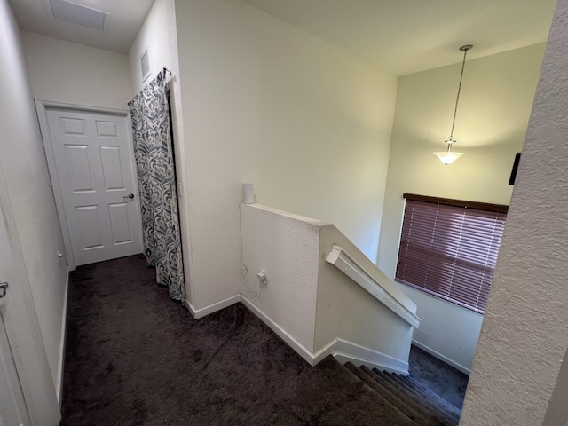 corridor with carpet floors, baseboards, visible vents, and an upstairs landing