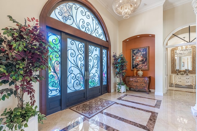 entryway featuring a high ceiling, ornamental molding, a notable chandelier, and french doors