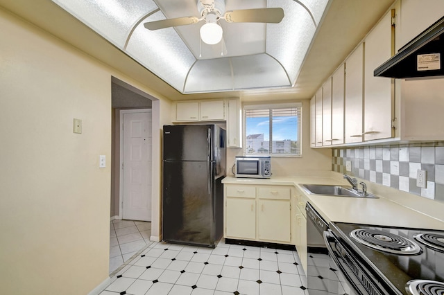 kitchen with sink, range hood, a tray ceiling, black appliances, and decorative backsplash