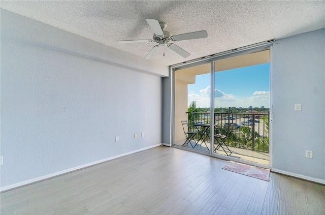 empty room featuring floor to ceiling windows, hardwood / wood-style floors, ceiling fan, and a textured ceiling