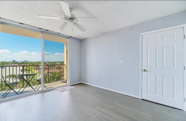 spare room with expansive windows, ceiling fan, hardwood / wood-style floors, and a textured ceiling