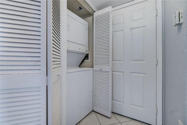 laundry room with light tile patterned flooring and stacked washing maching and dryer