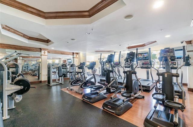 workout area featuring a raised ceiling and crown molding