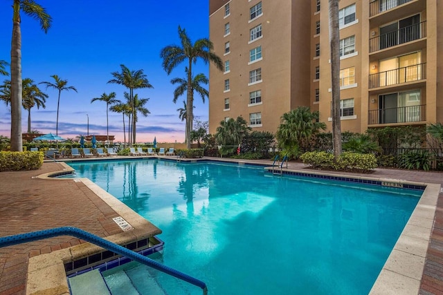 pool at dusk featuring a patio