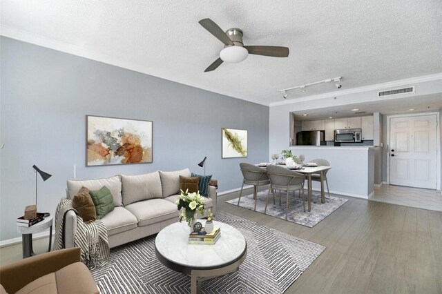 living room with ceiling fan, crown molding, a textured ceiling, and light hardwood / wood-style flooring