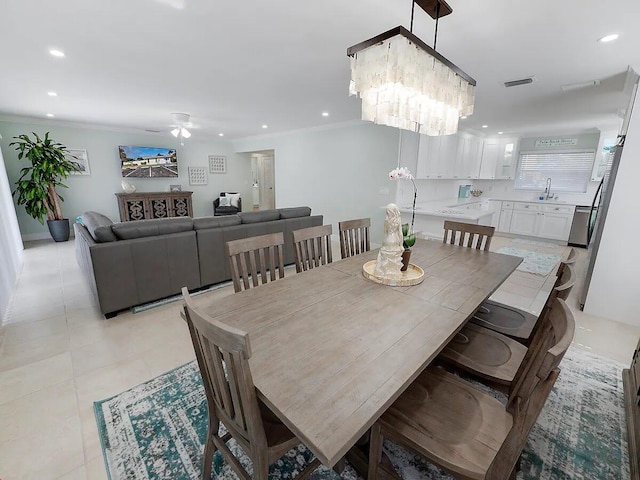 dining space with crown molding, sink, light tile patterned flooring, and ceiling fan with notable chandelier