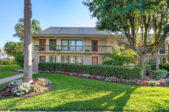 view of front of house featuring a balcony and a front lawn