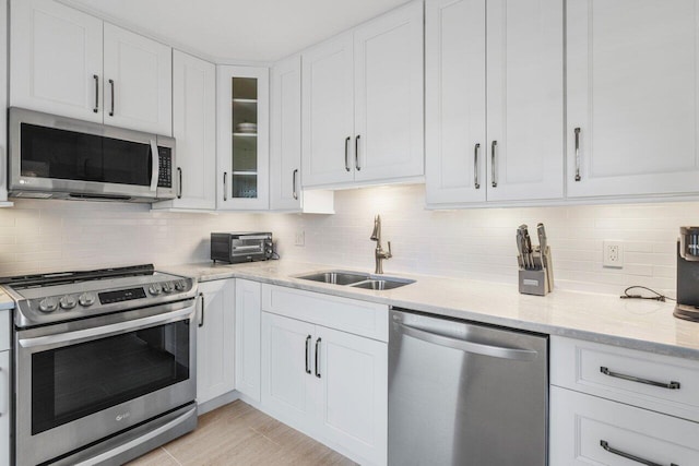 kitchen featuring sink, white cabinetry, tasteful backsplash, appliances with stainless steel finishes, and light stone countertops