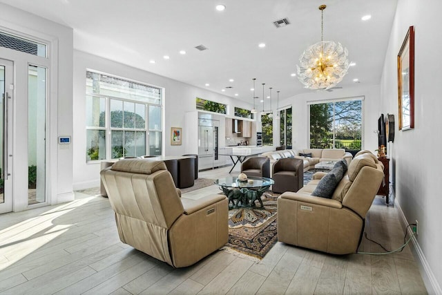 living room featuring an inviting chandelier, a wealth of natural light, and light wood-type flooring