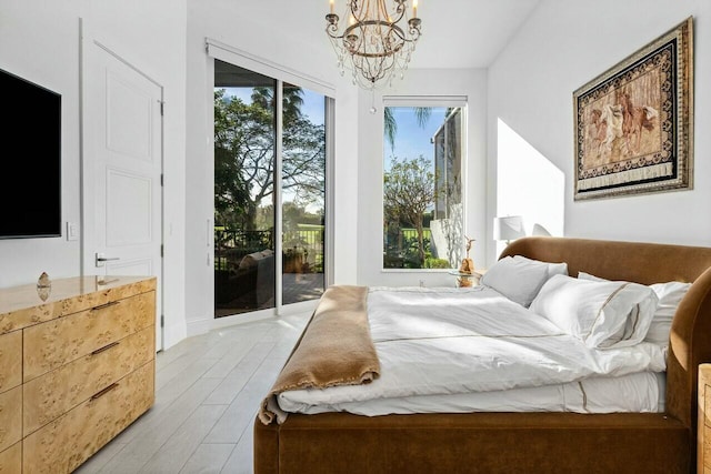 bedroom featuring a chandelier, light hardwood / wood-style flooring, and access to outside