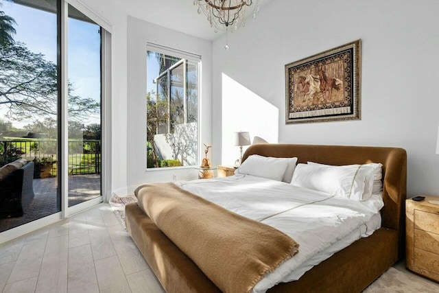 bedroom featuring an inviting chandelier, access to exterior, and light hardwood / wood-style flooring