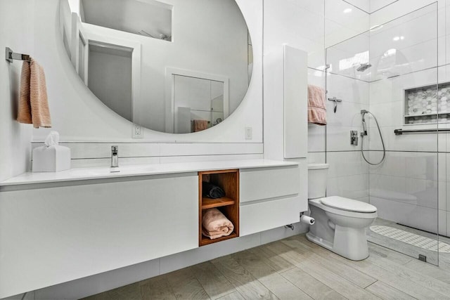 bathroom with vanity, toilet, and tiled shower