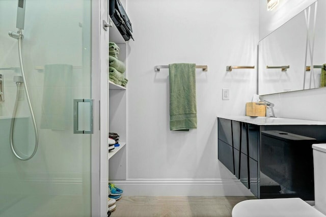 bathroom featuring vanity, a shower with shower door, and toilet