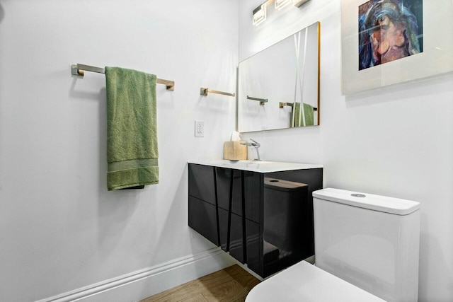 bathroom with vanity, toilet, and hardwood / wood-style floors