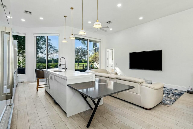 living room featuring ceiling fan, sink, and light wood-type flooring