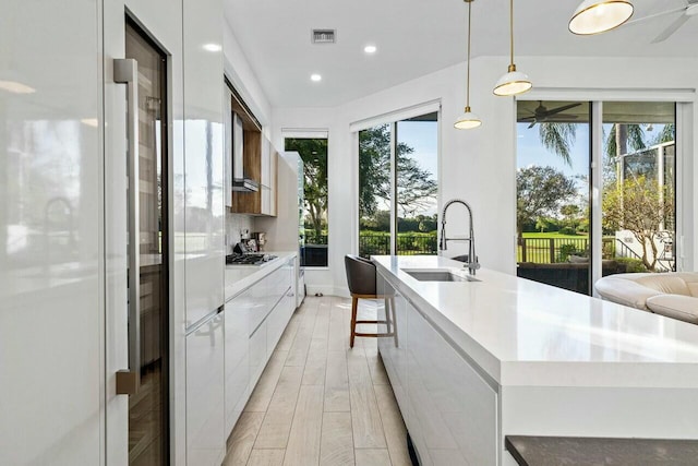 kitchen with a spacious island, sink, pendant lighting, a healthy amount of sunlight, and white cabinets