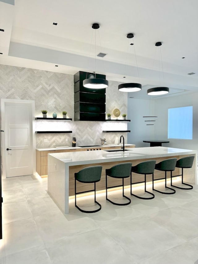 bar with sink, tasteful backsplash, decorative light fixtures, gas cooktop, and a tray ceiling