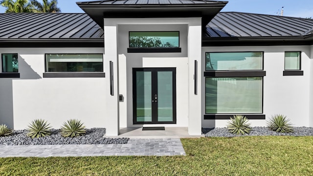 view of exterior entry with a yard and french doors