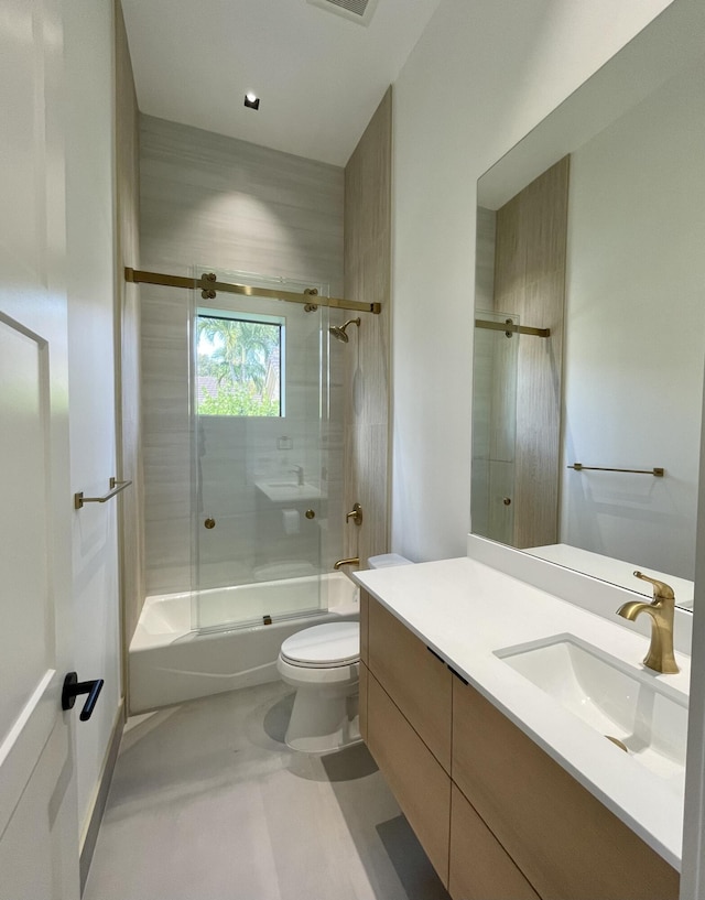 full bathroom with vanity, bath / shower combo with glass door, and toilet