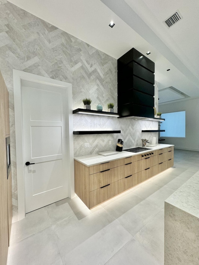 kitchen with gas stovetop, exhaust hood, backsplash, and light brown cabinetry