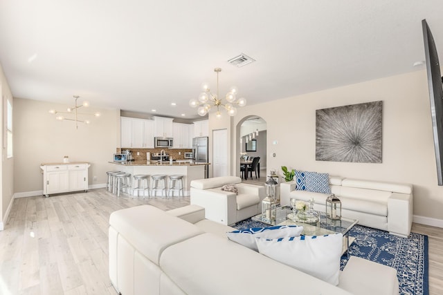 living room with an inviting chandelier and light hardwood / wood-style flooring