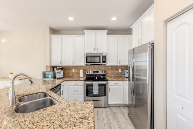 kitchen featuring white cabinetry, appliances with stainless steel finishes, light stone countertops, and sink