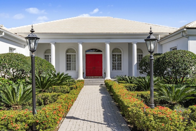 entrance to property with a tile roof and stucco siding