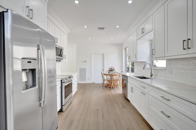 kitchen with backsplash, stainless steel appliances, sink, and white cabinets