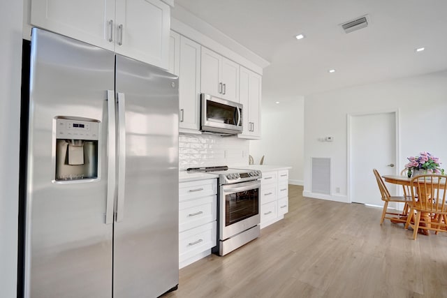 kitchen with decorative backsplash, stainless steel appliances, light hardwood / wood-style floors, and white cabinets