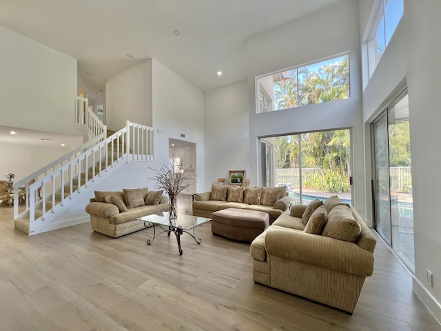 living room featuring a towering ceiling and light hardwood / wood-style flooring