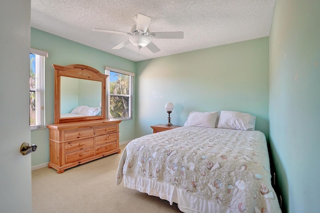 carpeted bedroom featuring ceiling fan and a textured ceiling