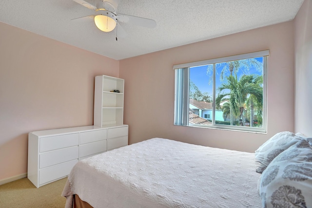 bedroom with ceiling fan, a textured ceiling, and carpet