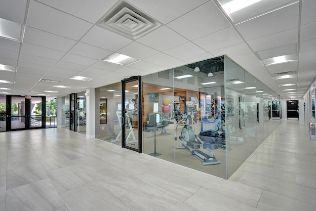 workout area featuring a drop ceiling, french doors, and expansive windows