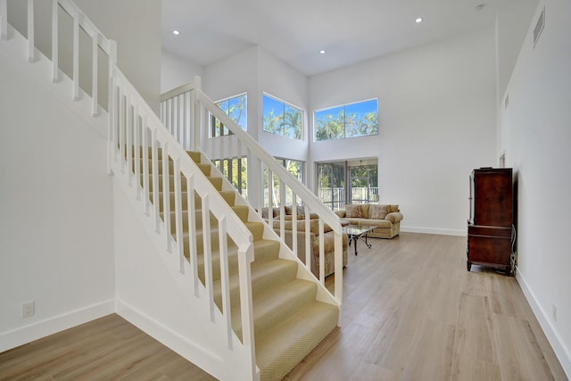 stairway with a high ceiling and wood-type flooring