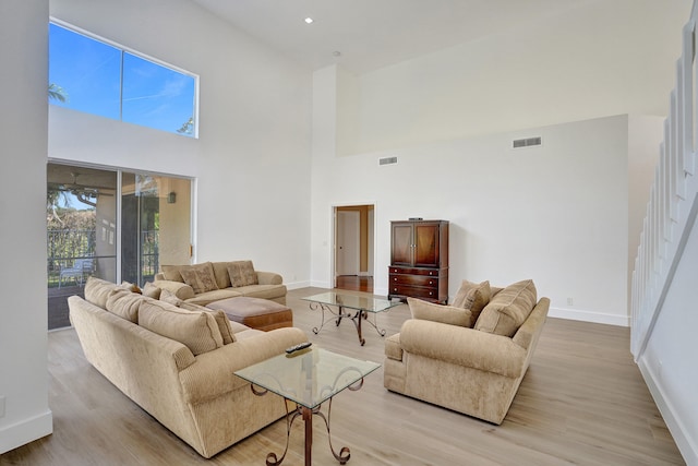 living room with a towering ceiling and light hardwood / wood-style floors