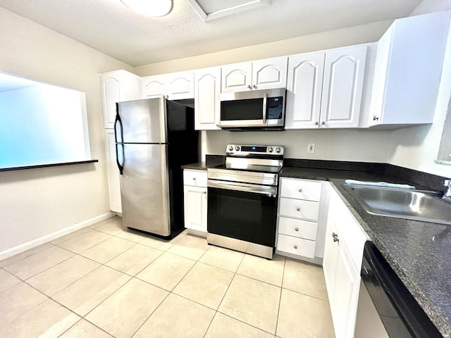 kitchen featuring appliances with stainless steel finishes, white cabinetry, sink, light tile patterned floors, and a textured ceiling