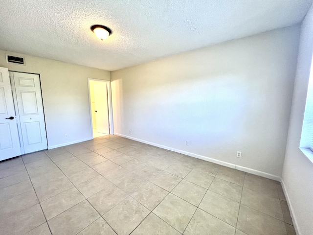 spare room with light tile patterned floors and a textured ceiling