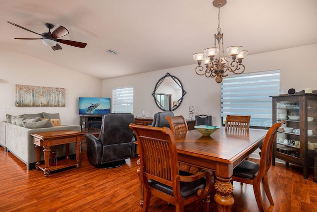 dining room with hardwood / wood-style floors, ceiling fan with notable chandelier, and vaulted ceiling