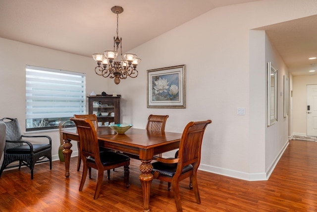 dining space featuring hardwood / wood-style flooring, vaulted ceiling, and a chandelier