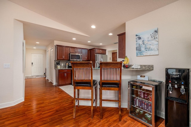 kitchen featuring light stone counters, stainless steel appliances, wood-type flooring, and decorative backsplash