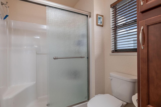 bathroom with a shower with door and toilet