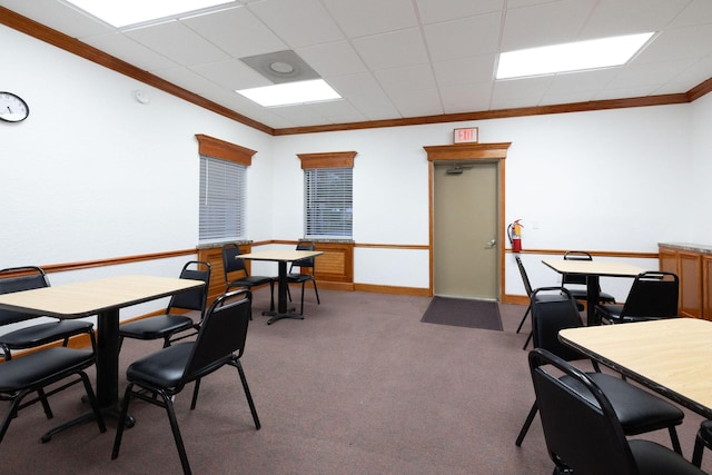 carpeted dining area featuring a drop ceiling and ornamental molding