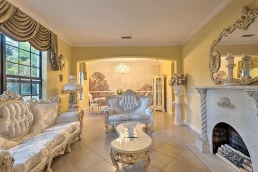 living area with crown molding, light tile patterned floors, and an inviting chandelier