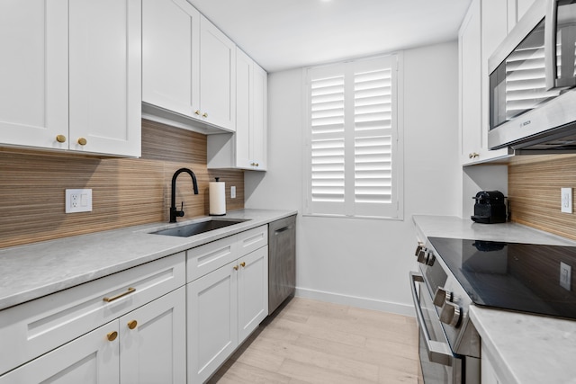 kitchen with white cabinetry, sink, decorative backsplash, and appliances with stainless steel finishes